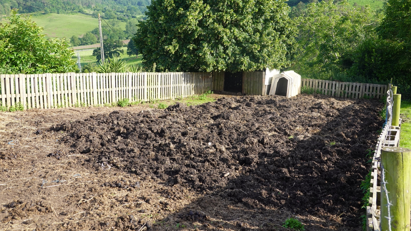 Freshly turned dark earth in a vegetable garden, with rows clearly defined, ready for cultivation and planting.