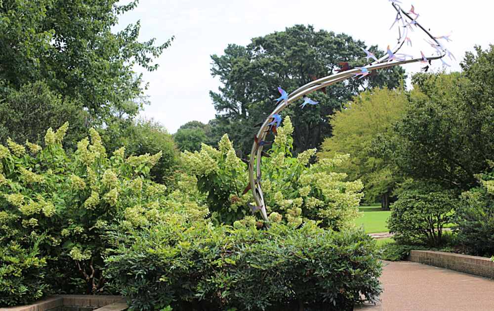 Sculpture of birds in flight in a botanical garden is used as an arch to connect visitors from one area to another..