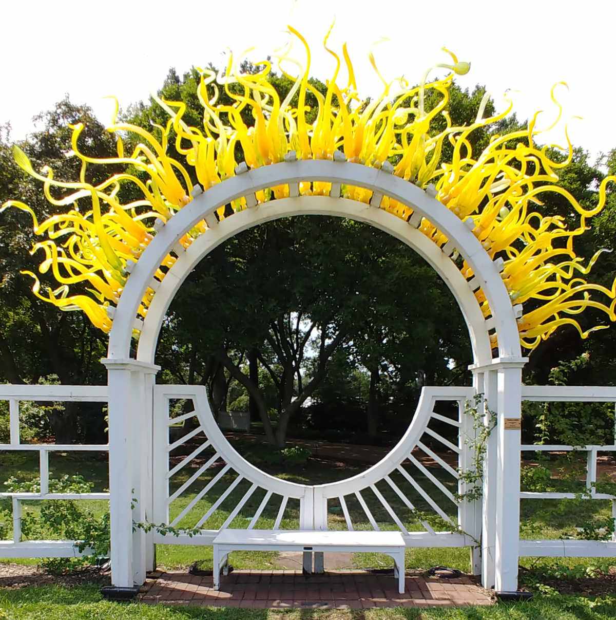 White arch with yellow plumes on the top. It doubles up as a seating area.